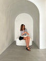 Person sitting on a white chair in a minimalist room with curved walls.