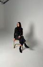 Woman sitting on a chair against a plain background