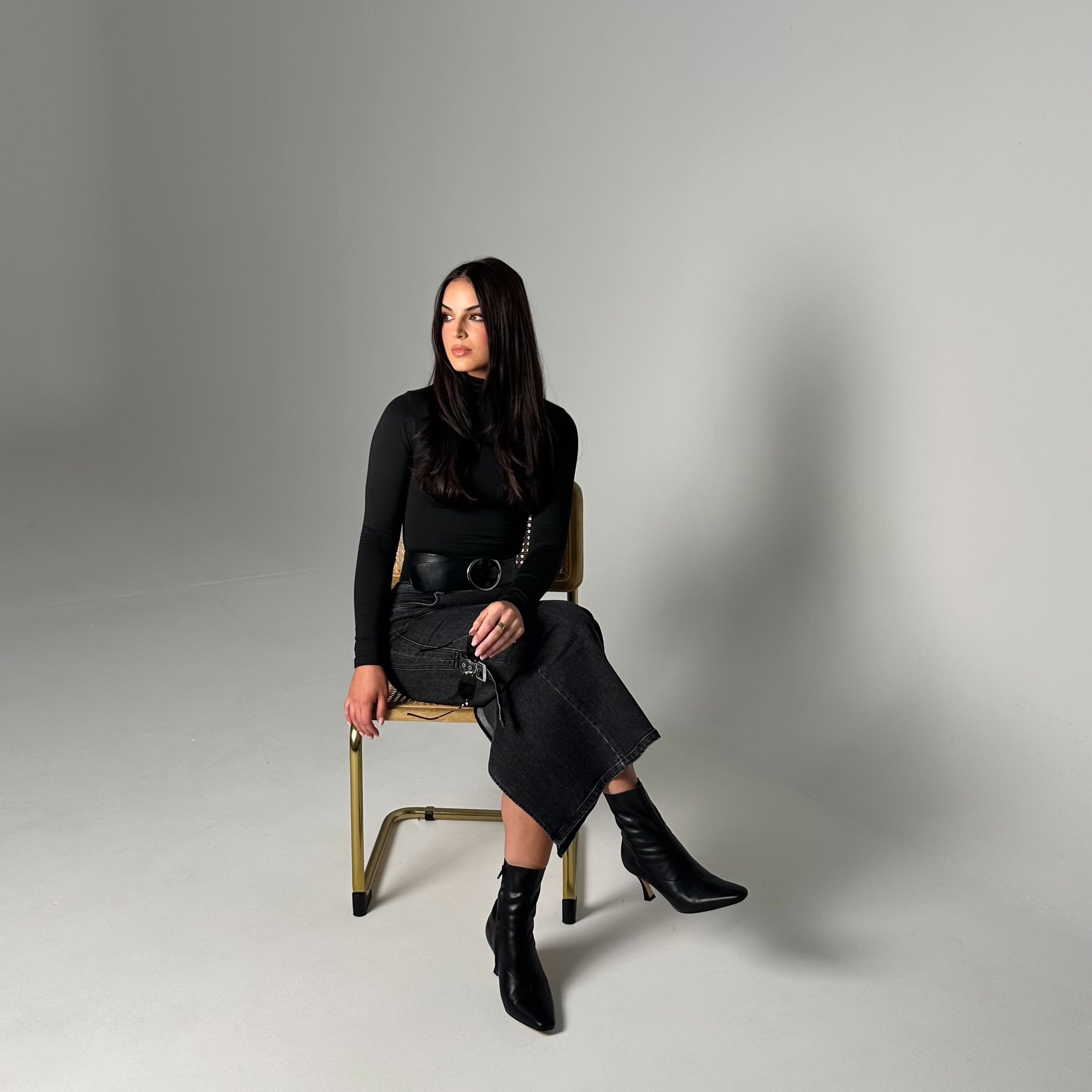 Woman sitting on a chair against a plain background