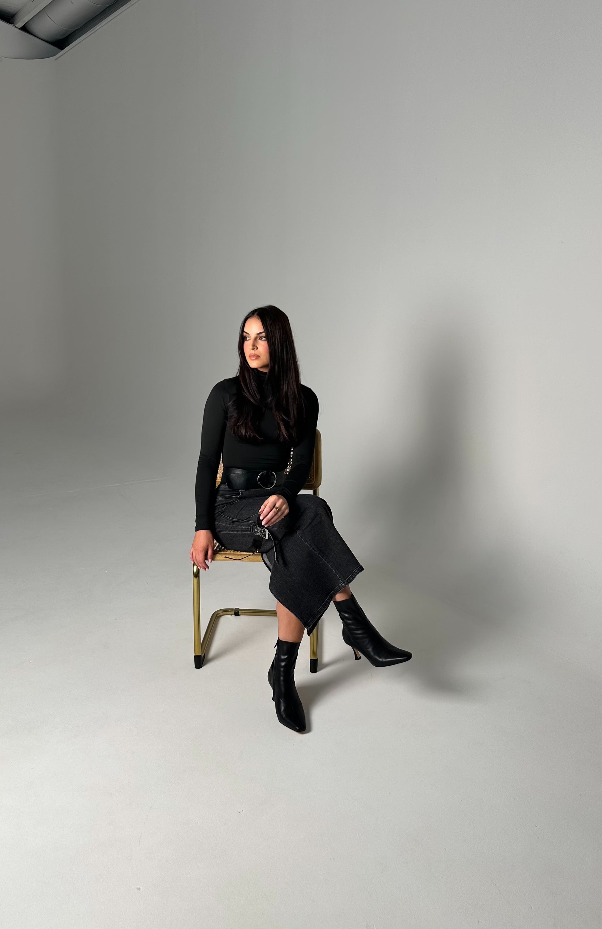 Woman sitting on a chair against a plain background