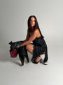 Woman in a black dress holding a red handbag on a gray background